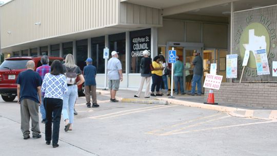 Voters stand outside at Taylor City Hall Tuesday evening waiting to cast their votes. Photo by Jason Hennington