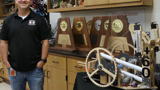 Lead Robotics Instructor Andrew Haub, coach of the Hutto HS robotics team known as RoboCo X, shows off the team trophies next to one of the winning robotics projects. Haub’s team has won four of the last five UIL state championships. Photos by Edie Zuvanich