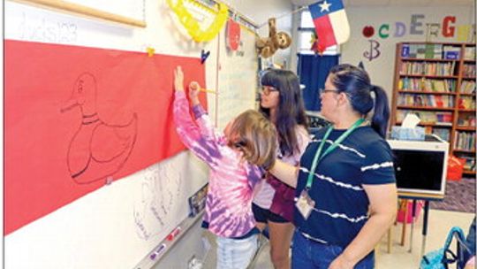 Mrs. Valerie Pugh assists her students in working on their class banner that will be displayed in the hallway at Main Street Elementary School. Their motto is We Are DUCKS: Determined, Understanding, Caring, Kind and Smart. The first through fifth grade campus will fill the hallways with c...