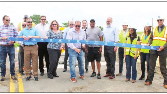 Officials and contractors celebrate the ribbon cutting to upgrades to County Road 101 May 4. Pictured (from left) are Oscar Salazar-Bueno, Steven Shull, Chief Scott Kerwood, Brian LaBorde, Scott Haywood, Christen Eschberger, Tom Yantis, Jeff Jenkins, Russ Boles, Gerald Anderson, Brandt Ryd...