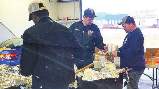 Firefighters serve the chili inside the fire station bay.