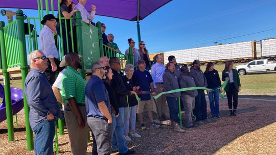 Irene Michna, a member of the Parks and Recreation Advisory Board, cuts the ribbon to ceremonially open the park, surrounded by community members, city staff and elected leaders, Oct. 26 at Doak Park. Photo by Nicole Lessin