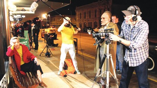 A scene from “Rondo and Bob” is shot outside 120Art in downtown Taylor. Pictured is Kirk Hunter on camera, Joseph Middleton as Rondo Hatton, and Joe O’Connell directing. Holding the boom microphone is Geo Rollier. Seated to the left is Kelsey Pribilski as Mae Hatton. Photo by Paul Smith