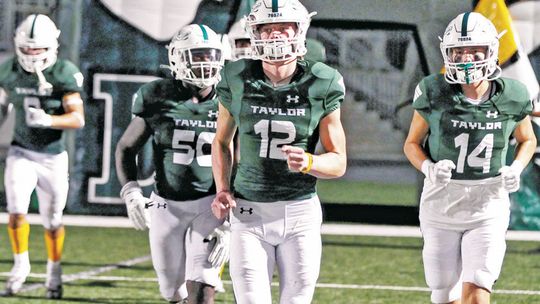 Taylor High School varsity football quarterback Joshua Mikulencak (12) runs out onto the field with teammates Alejandro Randle (50) and Jordan Pickerill (14) on Sept. 9, 2022, during the Ducks’ 41-19 home victory vs. Robinson High School. Photo by Larry Pelchat