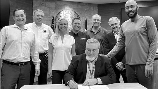 City Manager James Earp, seated, signs Cottonwood Properties ownership over to the EDC. Left to right: EDC board members Shawn Lucas, Mike Snyder, Erin Clancy and Randal Clark. Cottonwood Development Corporation member Peter Gordon. Director of Economic Development Bob Farley. EDC board me...