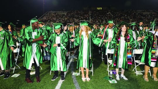 Grads locking pinkies for the singing of the school song on Friday, May 26. Photo by Tim Crow