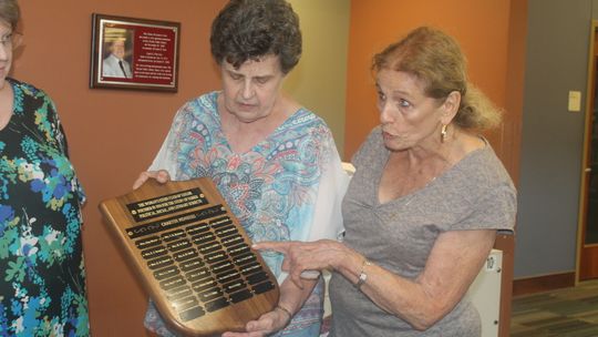 Katy Safark holds a plaque from the Woman’s Study Club as Rosemary Hauser discusses its importance during a presentation at the Taylor Public Library in Taylor April 13.