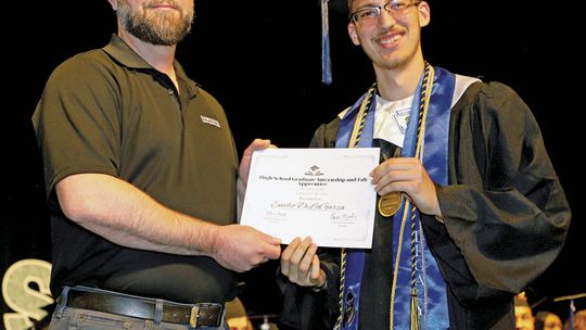 Emilio DeLaGarza, a 2023 Legacy Early College High School graduate, is awarded a post graduate internship at Samsung during graduation ceremonies in May. Making the presentation is Mike Stebbins from Samsung. Photo by Tim Crow