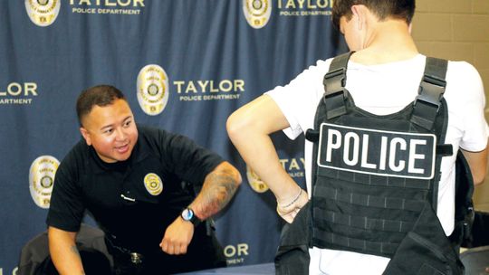 Taylor policer officer Michael McIntire helps a student try on a tactical vest at the Trades Day hosted by the Greater Taylor Chamber of Commerce last week. Photos by Edie Zuvanich