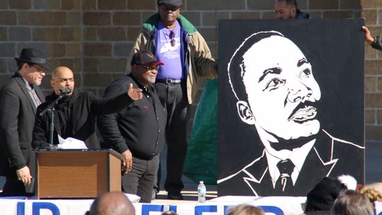 Stephen Michael Johnson (center) talks about the significance of Dr. Martin Luther King Jr. as his painting is unveiled by (from left) Rev. Anthony Watson, Shorty Mitchell and Nelson Alexander. Photo by Jason Hennington