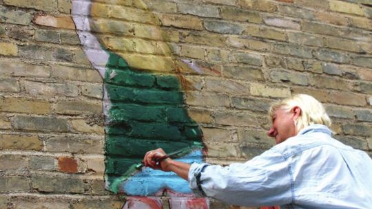 Judy Blundell paints a little girl holding on to a red balloon in Potter’s Alley. Photo by Jason Hennington