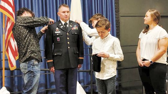 Sons Jackson Meller (left) and Joshua Meller attach shoulder boards displaying Joseph Meller’s new rank as an Army lieutenant colonel; youngest son John Meller pins his dad’s beret Feb. 8 during the promotion ceremony at Camp Mabry as wife Rhonda Meller looks on. The family calls Taylor ho...