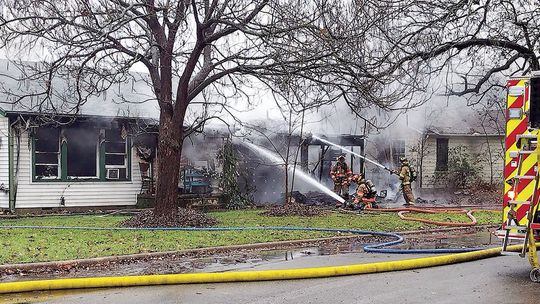 Firefighters extinguish a house fire Monday afternoon at Fisher and Kimbro streets. Photo by Jason Hennington