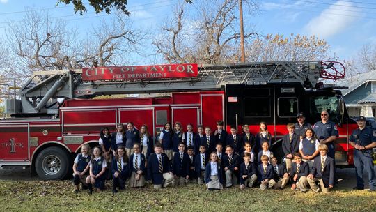 St. Mary’s fifth and sixth graders pose with the fire fighters after loading their truck with donated toys.