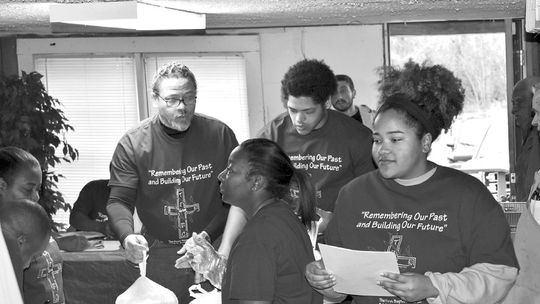 Pastor Anthony Watson helps members prepare Thanksgiving dinners at The First Baptist Church. Watson will celebrate 25 years, the longest tenure for a pastor at the church, Sunday, July 23 during the 10:45 a.m. service. Courtesy photo