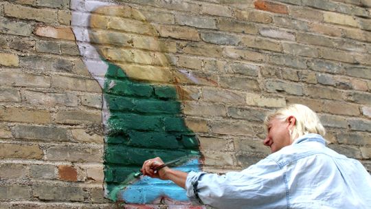 Judy Blundell paints a little girl holding on to a red balloon in Potter’s Alley. Photo by Jason Hennington