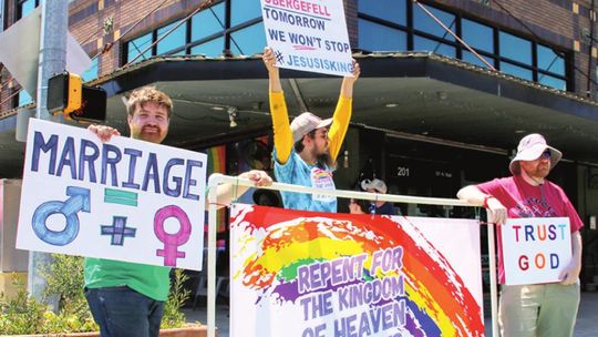 Protesters (from left) Bradley Machita, Spencer Ripple and Chris Connell stand at the corner of Second and Main streets with a different message during the PRIDE festival. Photo by Jason Hennington