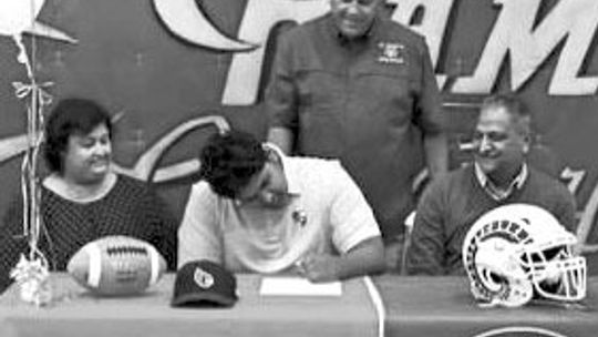 Flanked by his parents Daniel Vincent puts pen to paper to sign his letter of intent. Courtesy photo