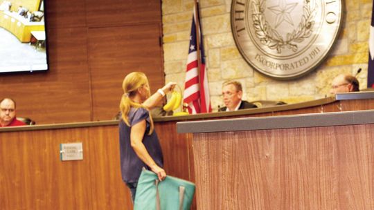Hutto resident Nicole Calderon presents the mayor with bananas to illustrate her view of city council’s behavior. Photo by Edie Zuvanich