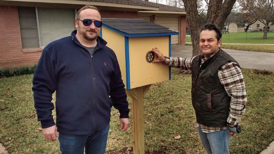 Rotary club members Ryan Stiba and Jim Buzan pose next to the new Little Free Library they helped install Dec. 16 in front of the church offices on Seventh Street in Taylor.