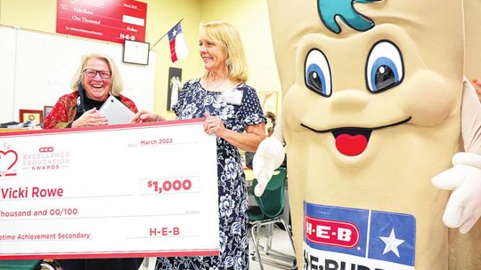 Taylor High School teacher Vicki Rowe is surprised with the HEB Excellence Award by HEB representatives Jill Reynolds and H-E-BUDDY. Photo by Ryan Newsom