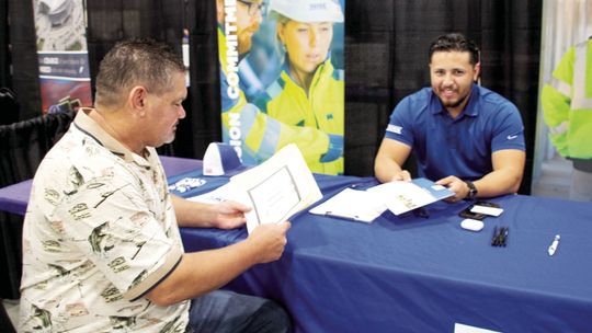 Joshua Mena, a recruiter for Yates Construction, chats with job seeker Edward Betak Jr. a Sept. 1 job fair hosted by Samsung Austin Semiconductor at the Williamson County Expo Center Photo by Nicole Lessin