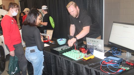 Brandon States talks with students at the Tesla table at the Greater Taylor Chamber of Commerce Trades Day career fair at the Williamson County Expo Center in Taylor March 2.