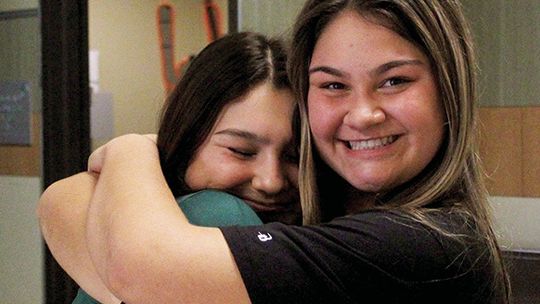 Makenna (left) and Mackenzie share a hug before volleyball practice at Taylor High School. Photo by Evan Hale