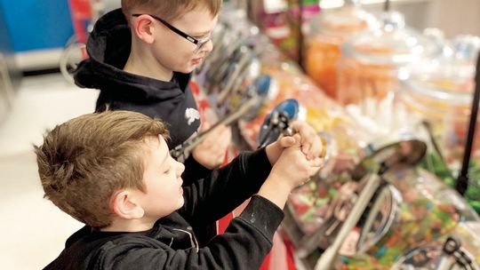 Olin Petke Jr., 9, and Ostin Petke, 4, gather candy at their father’s store Jan. 30. Fudge in the shape of Texas (top left) are on display at Big O’s Classic Candy and Nitrogen Ice Cream. A batch of heart-shaped candies (top right) filled with Heath Bars and peanut butter await Valentine’s...