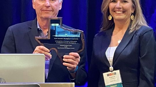 Mark Thomas, president of Taylor EDC, holds a Community Economic Development Award from the Texas Economic Development Council with Regina Jo Carlson, Taylor EDC’s business development manager. Photo by Nicole Lessin