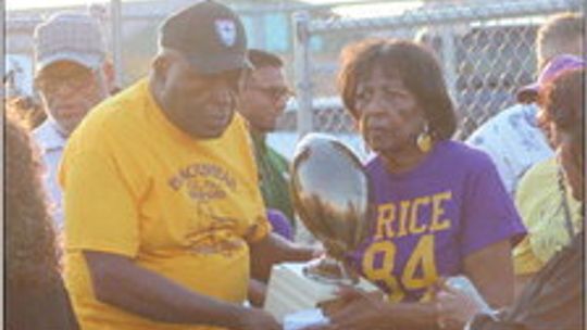 Former mayor Don Hill and wife Leslie carry the 1961 state championship trophy to the field. Photo by Catherine McGary