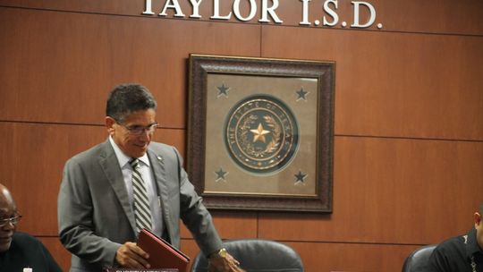 Steve Flores, Taylor Independent School District's new interim superintendent, ceremoniously joins the trustees at the school board meeting. Photo by Hunter Dworaczyk.