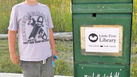 Augie Bidwell with his new Little Free Library, courtesy of the Elgin Courier and its sister paper, the Taylor Press. The sign is a work in progress, his family said. Courtesy photo/Elisha Bidwell