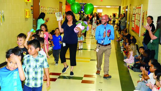 T. H. Johnson Elementary students and staff celebrate their Teacher of the Year, Lucia Arellano, in a parade around the campus. Arellano is accompanied by her class and by Principal Andy Basche. Photo by Tim Crow