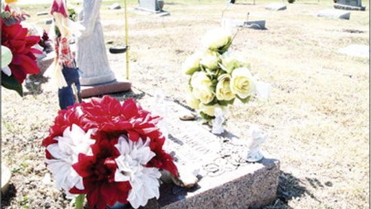 Several crosses and angel statues decorate a grave at the Taylor Cemetery. Most memorial items are prohibited under a municipal ordinance. Photos by Nicole Lessin