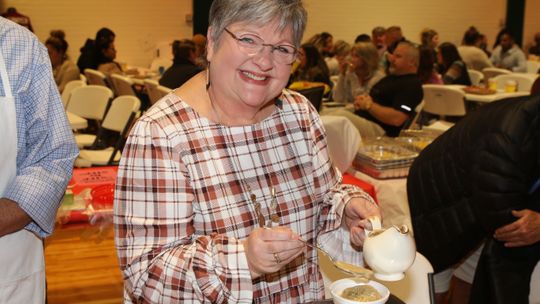 Anita Volek serves up a sample of dressing and gravy at this year’s Food Dudes event, sponsored by the TEE Foundation.   Photo by Tim Crow