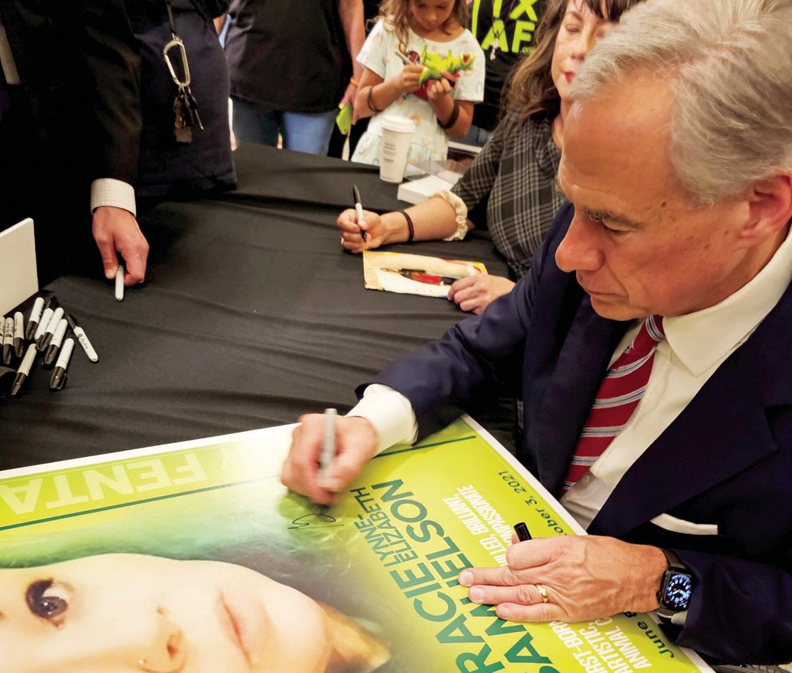 Gov. Greg Abbott writes on a poster bearing Grace Samuelson’s image June 14 after signing into law four fentanyl-related bills. The 29-year-old woman died Oct. 3, 2021, from fentanyl poisoning. Courtesy photo