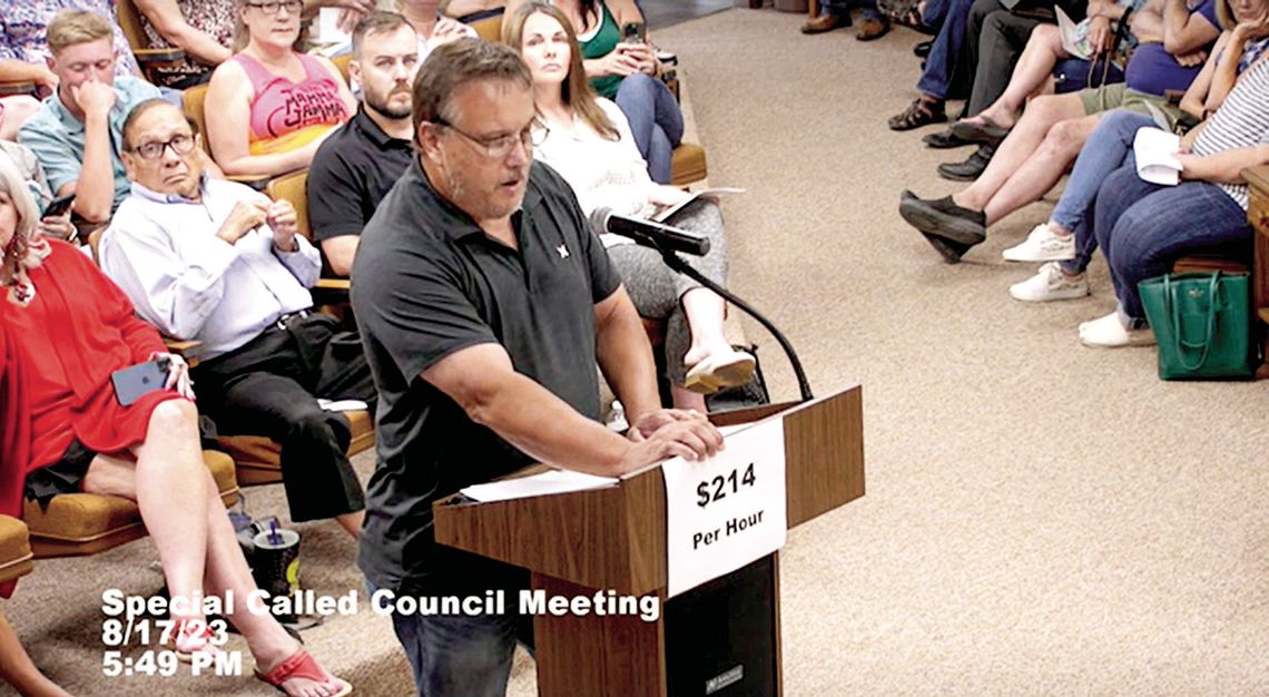 Gary Gola, a citizen speaker who was against the ordinance, holds a sign that says “$214 per hour.” Screenshot from Taylor City Council meeting