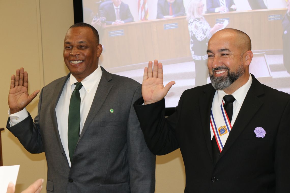 Gerald Anderson (left) and Robert Garcia smile as they are sworn-in to continue their service as city councilmen for Districts 1 and 4, respectively. 