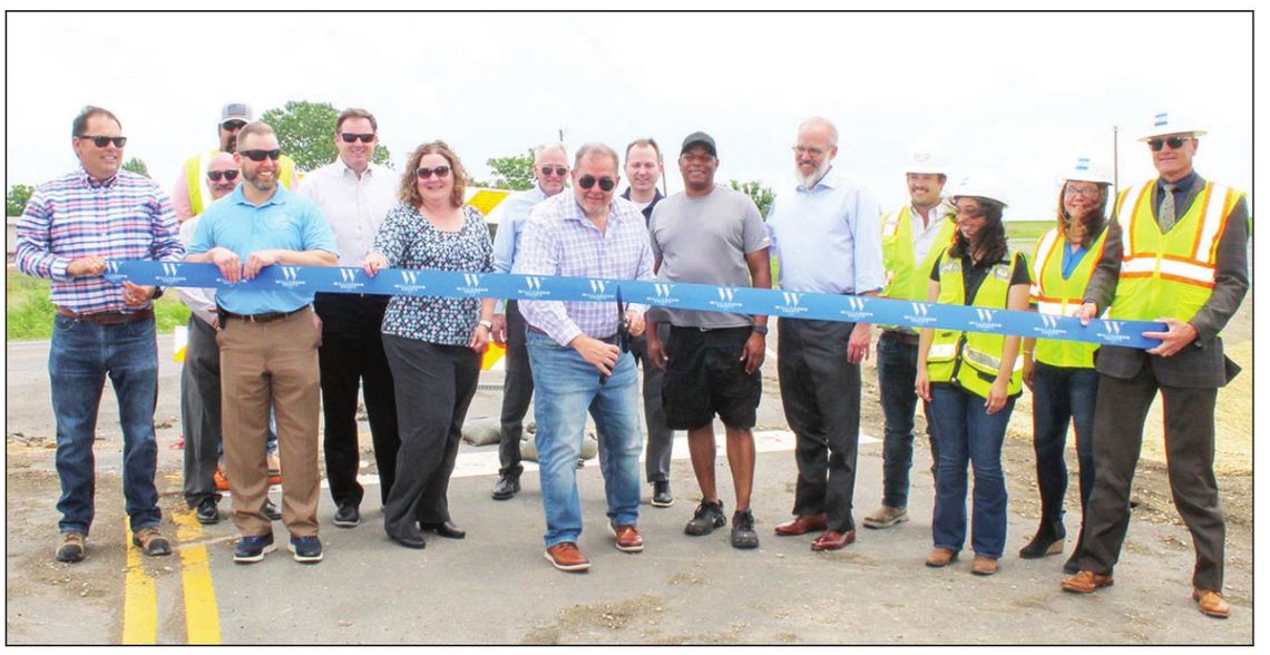 Officials and contractors celebrate the ribbon cutting to upgrades to County Road 101 May 4. Pictured (from left) are Oscar Salazar-Bueno, Steven Shull, Chief Scott Kerwood, Brian LaBorde, Scott Haywood, Christen Eschberger, Tom Yantis, Jeff Jenkins, Russ Boles, Gerald Anderson, Brandt Ryd...