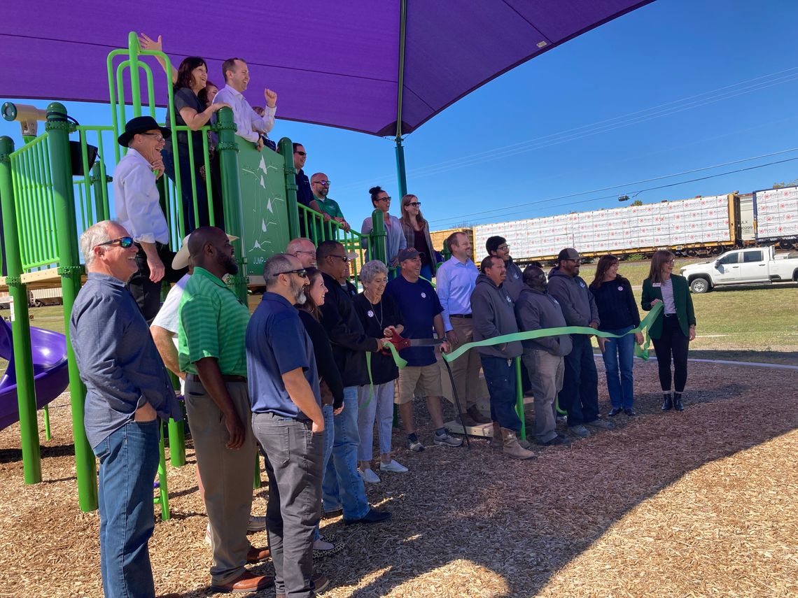 Irene Michna, a member of the Parks and Recreation Advisory Board, cuts the ribbon to ceremonially open the park, surrounded by community members, city staff and elected leaders, Oct. 26 at Doak Park. Photo by Nicole Lessin