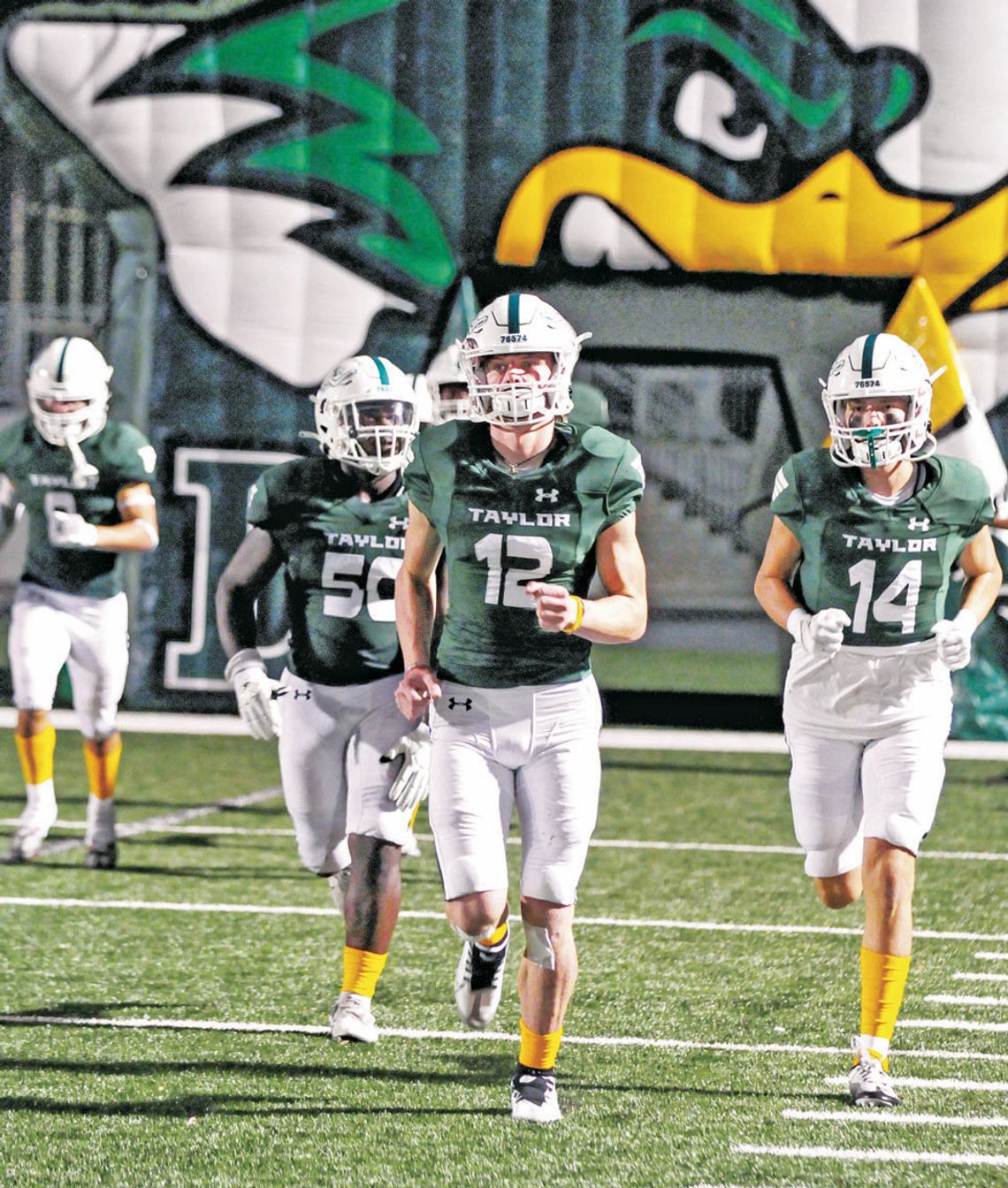 Taylor High School varsity football quarterback Joshua Mikulencak (12) runs out onto the field with teammates Alejandro Randle (50) and Jordan Pickerill (14) on Sept. 9, 2022, during the Ducks’ 41-19 home victory vs. Robinson High School. Photo by Larry Pelchat