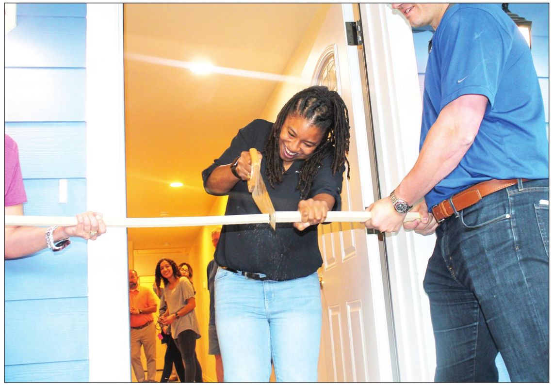 Ashley Molock cuts a ceremonial board April 27 officially opening her house in Taylor. Photo by Fernando Castro