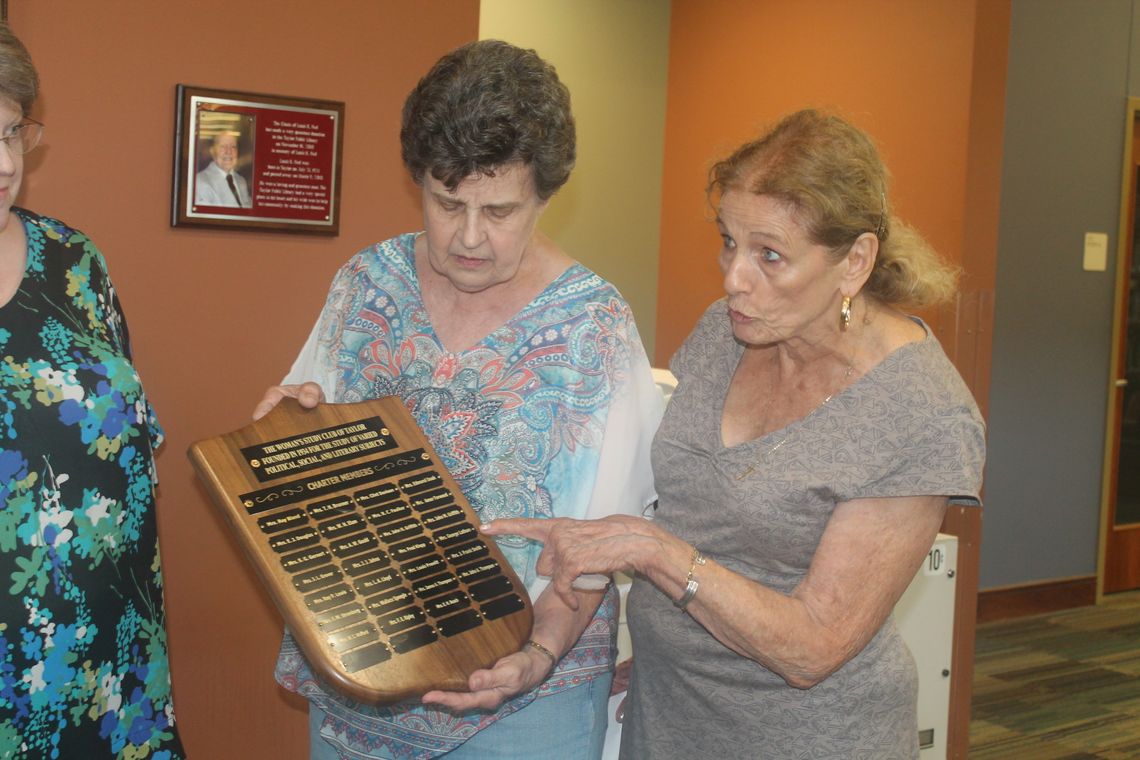 Katy Safark holds a plaque from the Woman’s Study Club as Rosemary Hauser discusses its importance during a presentation at the Taylor Public Library in Taylor April 13.