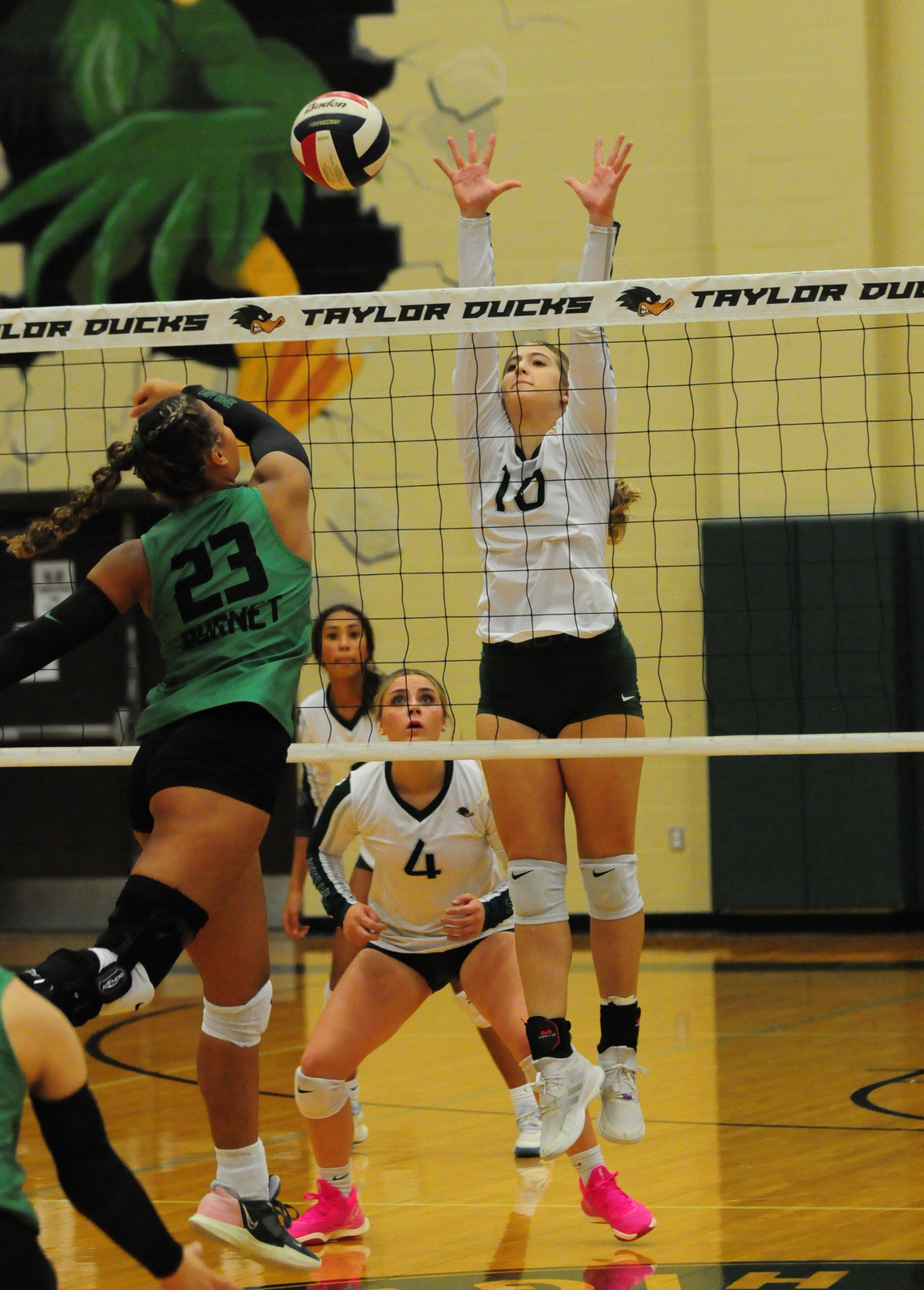 Taylor High School varsity volleyball senior Ansley Reed (10) goes up to block a shot at the net while fellow senior Camryn Nunamaker (4) looks on during the Lady Ducks’ home match victory vs. Burnet High School on Tuesday night. Photo by Larry Pelchat 
