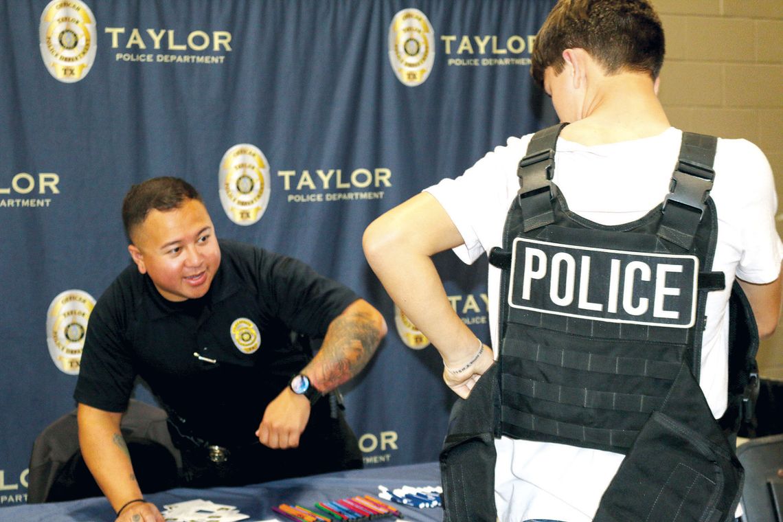 Taylor policer officer Michael McIntire helps a student try on a tactical vest at the Trades Day hosted by the Greater Taylor Chamber of Commerce last week. Photos by Edie Zuvanich