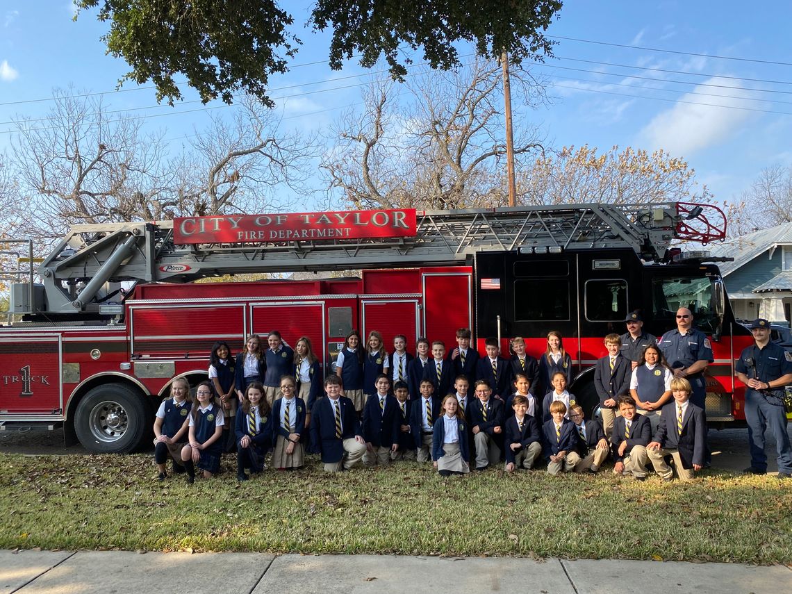 St. Mary’s fifth and sixth graders pose with the fire fighters after loading their truck with donated toys.