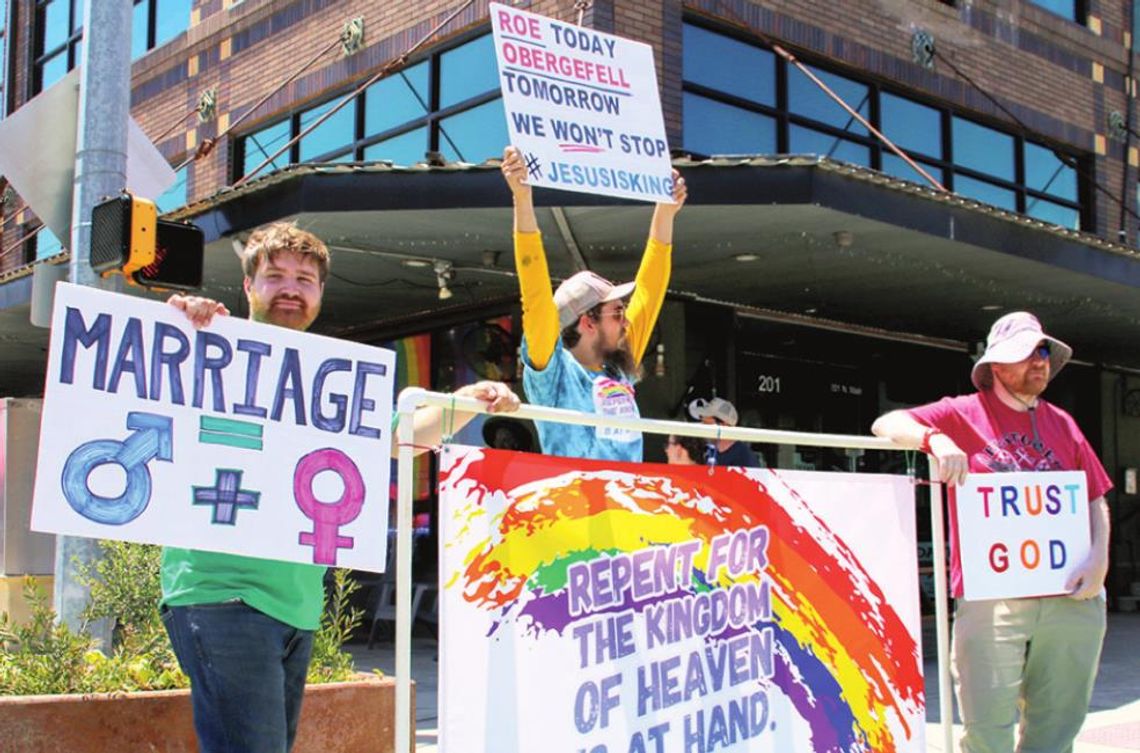 Protesters (from left) Bradley Machita, Spencer Ripple and Chris Connell stand at the corner of Second and Main streets with a different message during the PRIDE festival. Photo by Jason Hennington