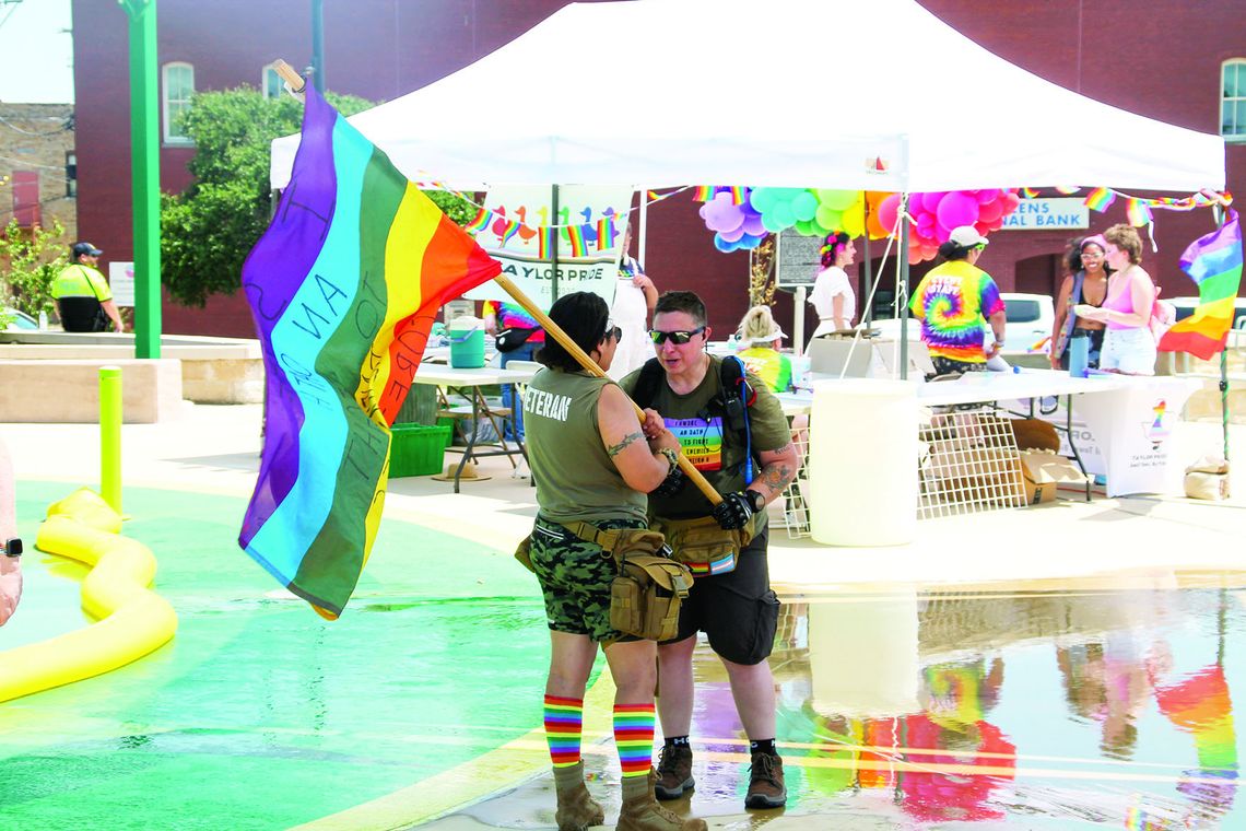 Gen Peńa of Veterans for Equality stands with a Pride flag near the splash pad area of Heritage Park. Photo by Hunter Dworaczyk