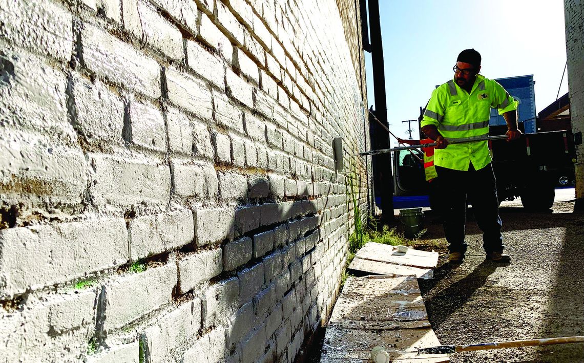 Taylor public works staffer Chris Gonzales applies a new coat of paint Sept. 30 to the wall on the north side of Potter’s Alley. Photo by Richard Stone